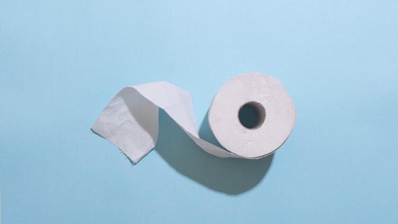 Roll of toilet paper on light blue background.