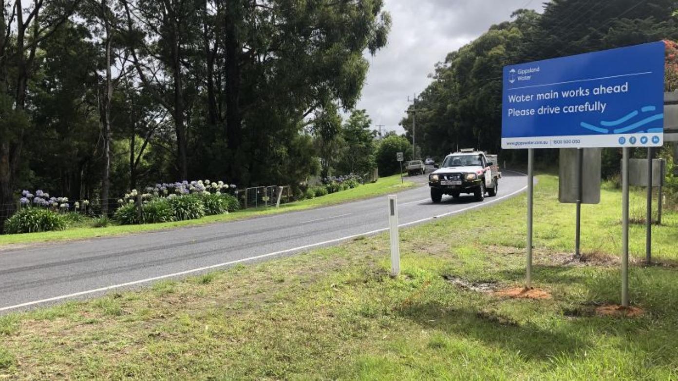 Car drives down road next to blue Gippsland Water sign.