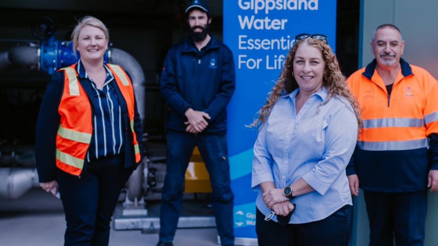 Four people stand in front of Gippsland Water sign