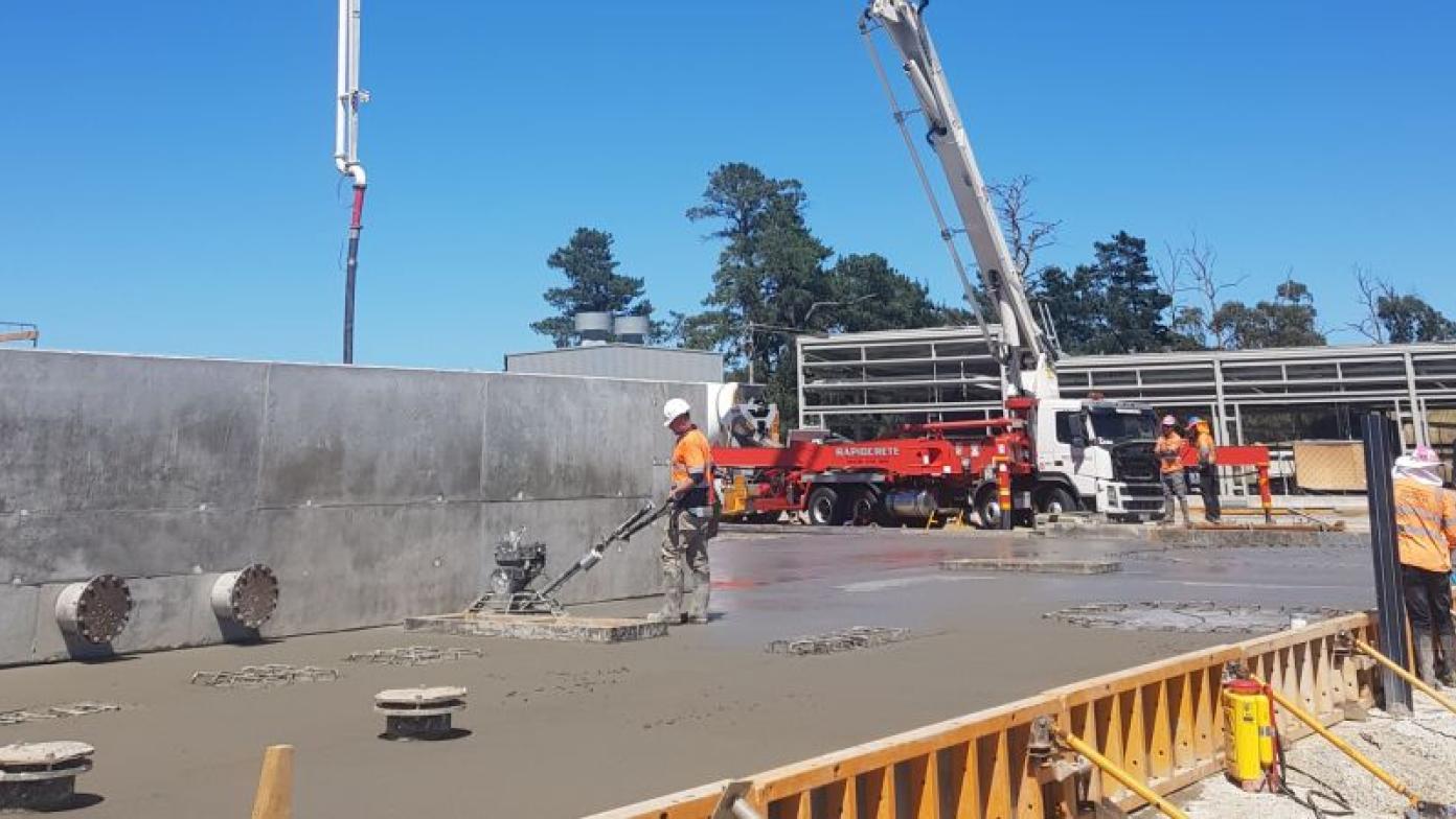 Construction taking place. Fresh concrete on ground and crane.