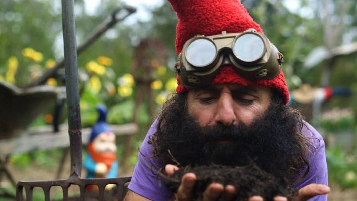 Man dressed as elf holds soil in his hands.