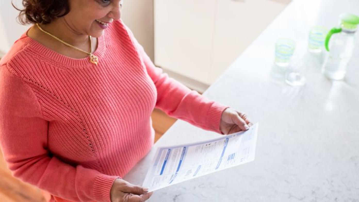 Woman smiles while holding a Gippsland water bill. 