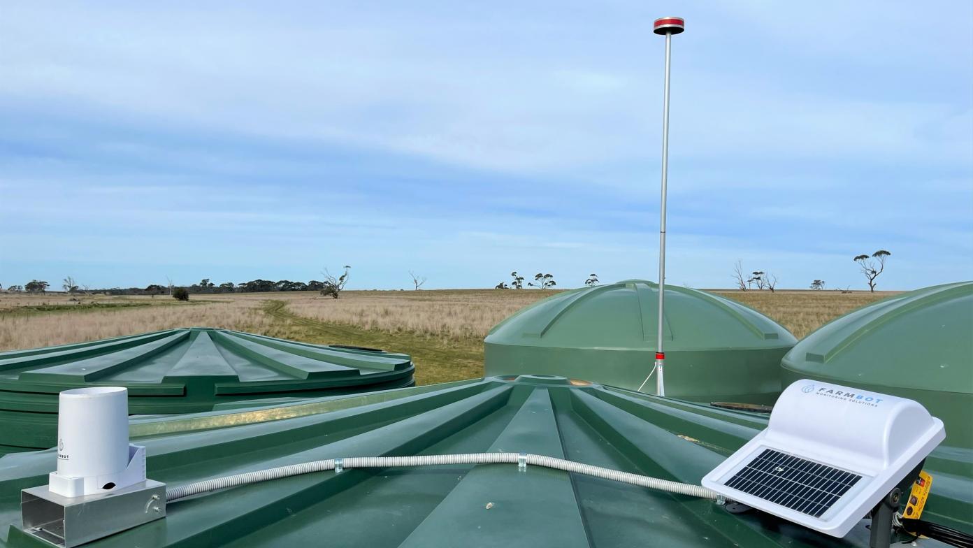 The top of a green water tank with a white square farmbot on top. 