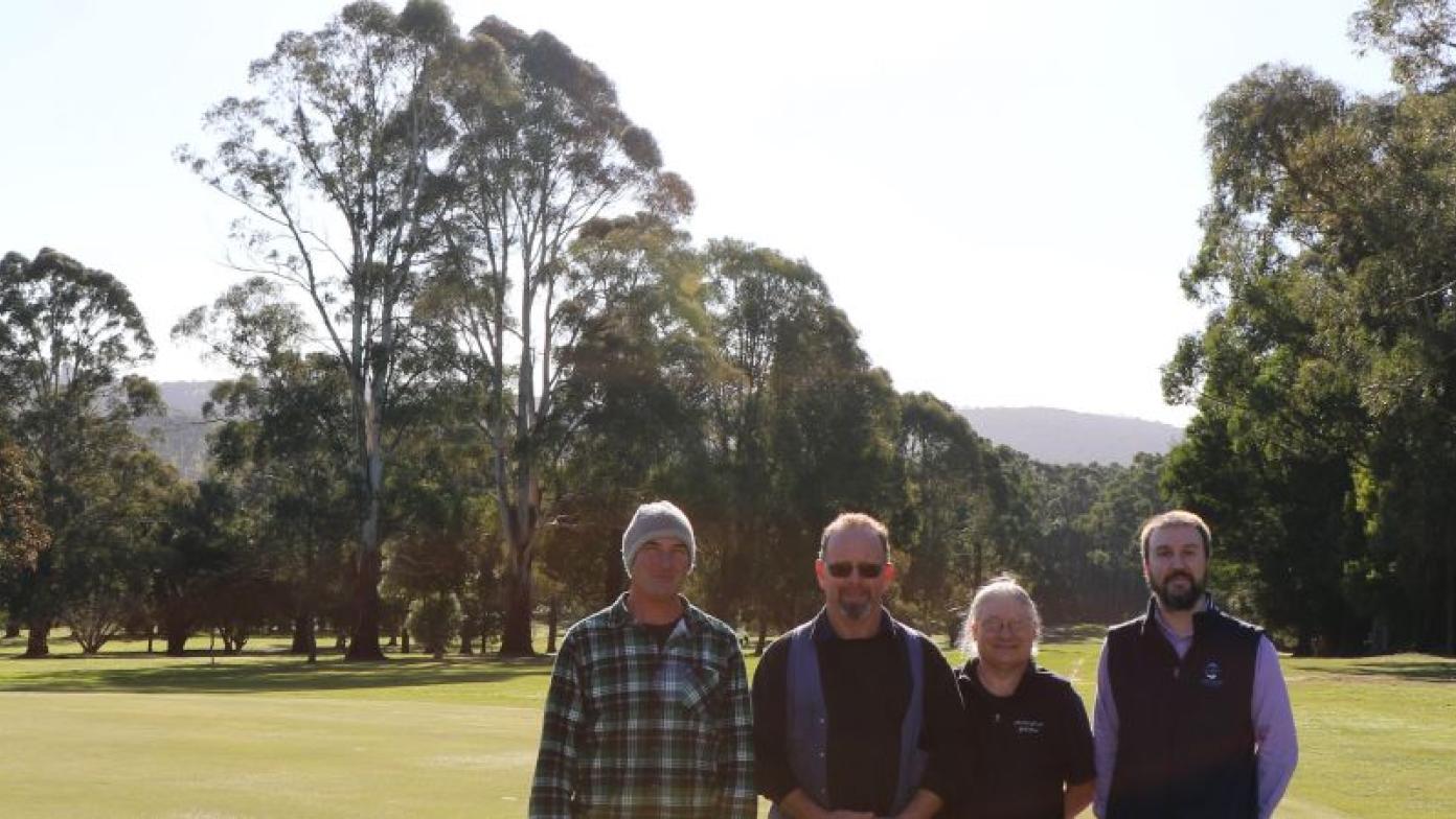 Four people stand on a green. 