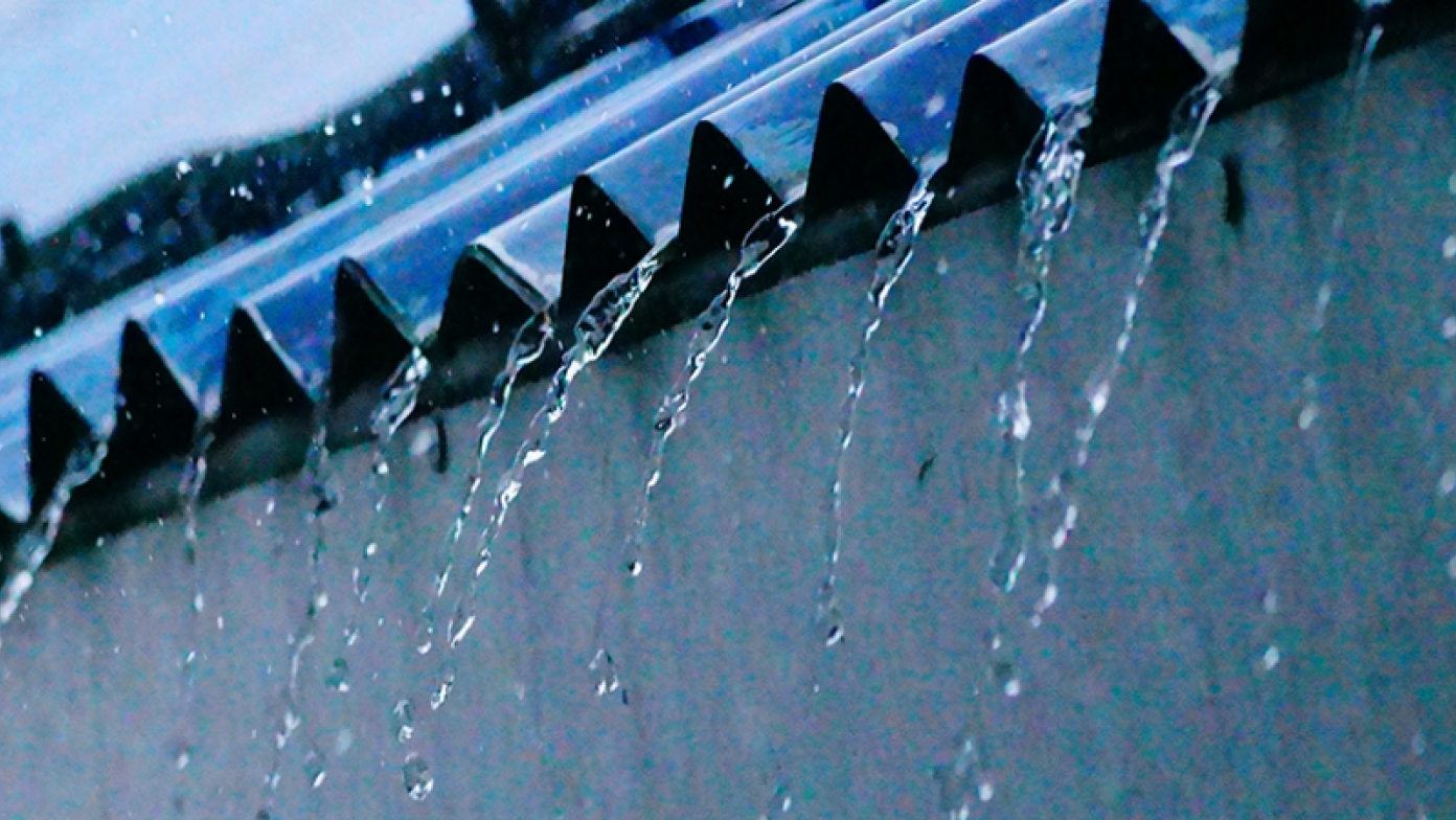 Water falls from edge of tin roof. 