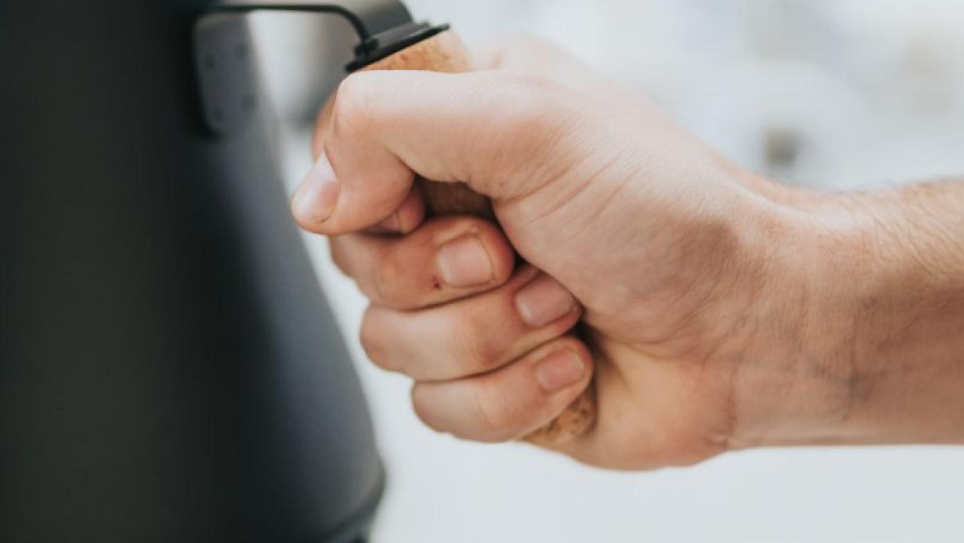 Person holds handle of kettle.