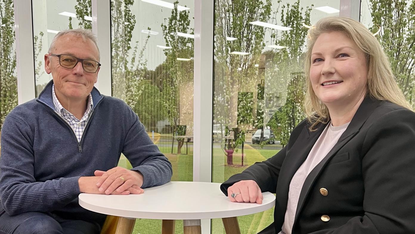 Man and woman sit together at table. They smile at camera