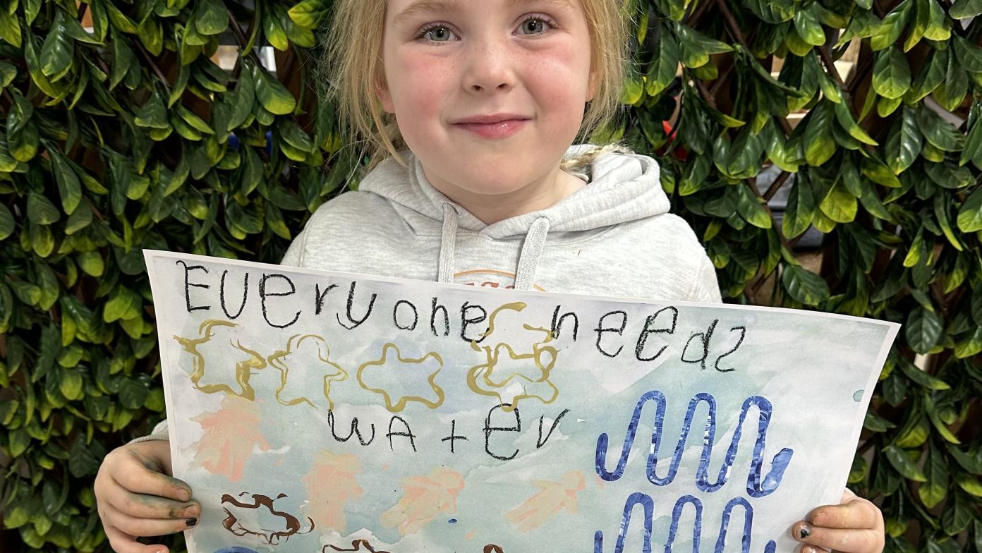 Young girl holds up drawing