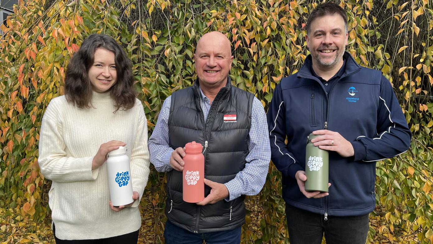 Jess, Nigel and Michael smiling and looking at the camera holding Drink Gippy Tap premium charity water bottles. 