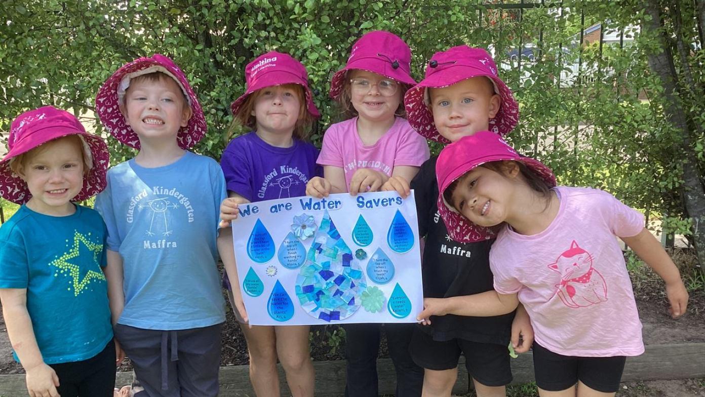 Six children hold water themed poster