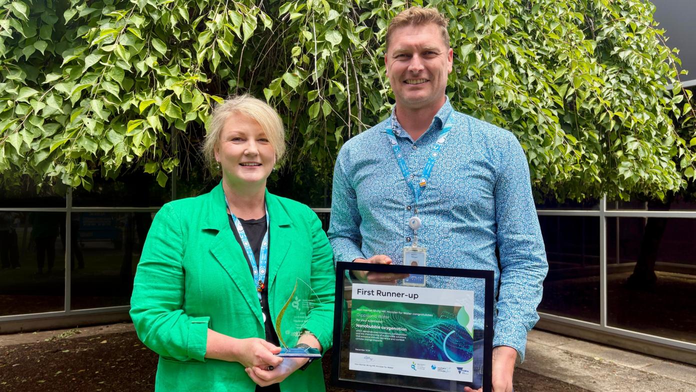 Two people hold certificate and glass trophy