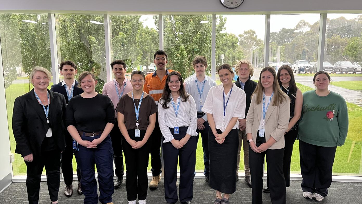 Students and managing director in two rows in front of window. 