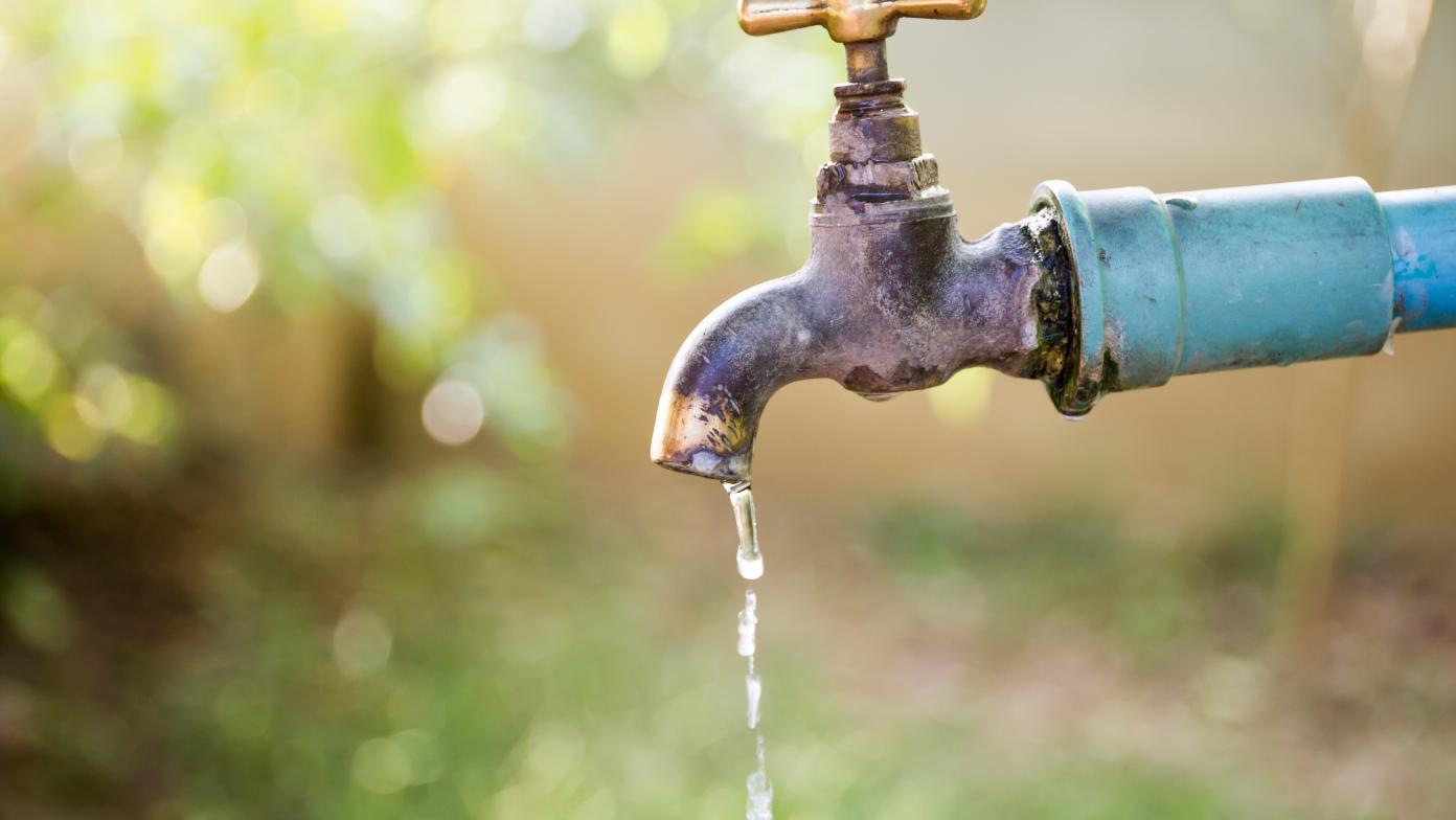 A leaking tap in a green garden