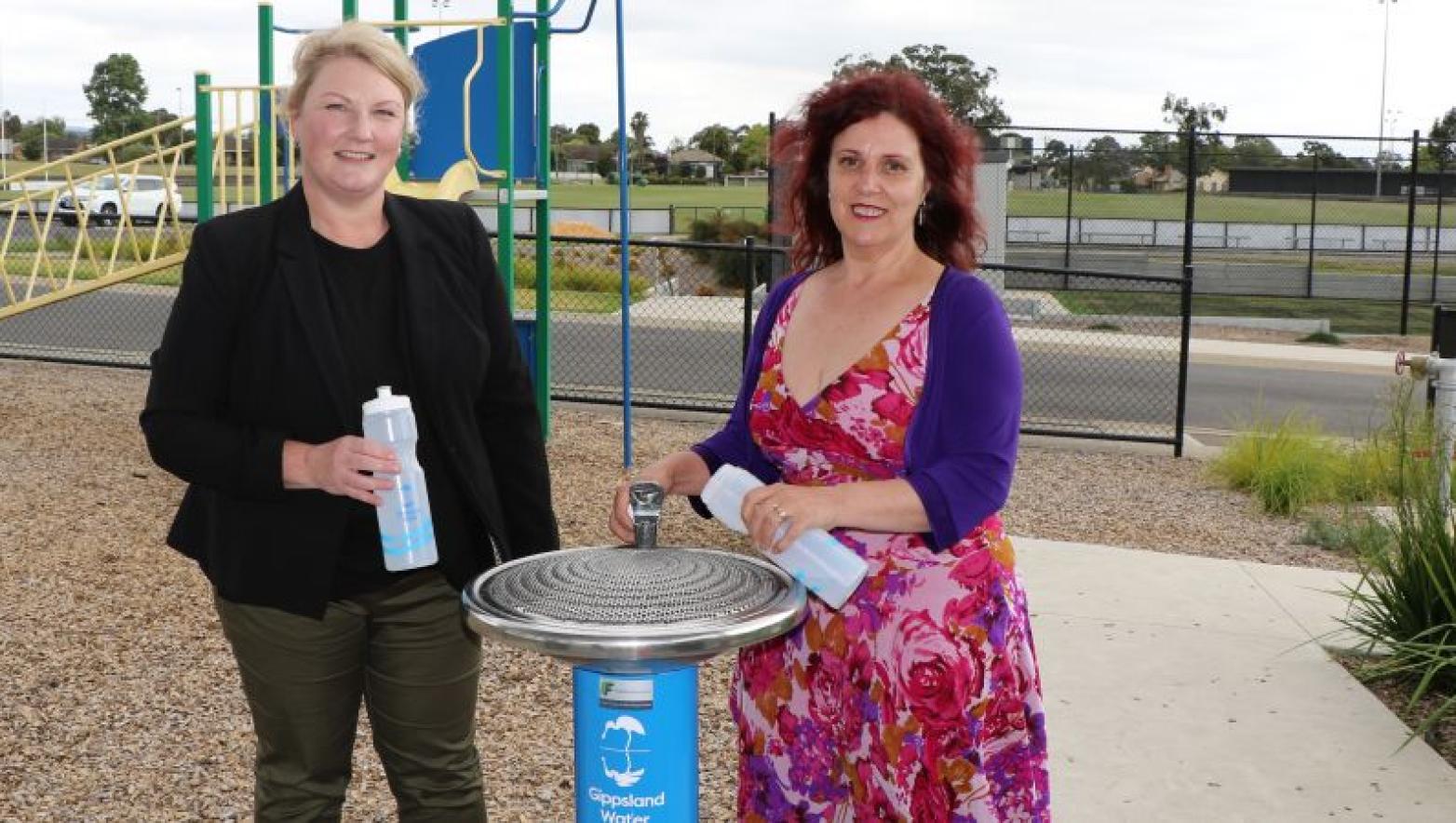 Sarah Cumming and Sharon Gibson stand on either side of Gippsland Water drinking fountain.