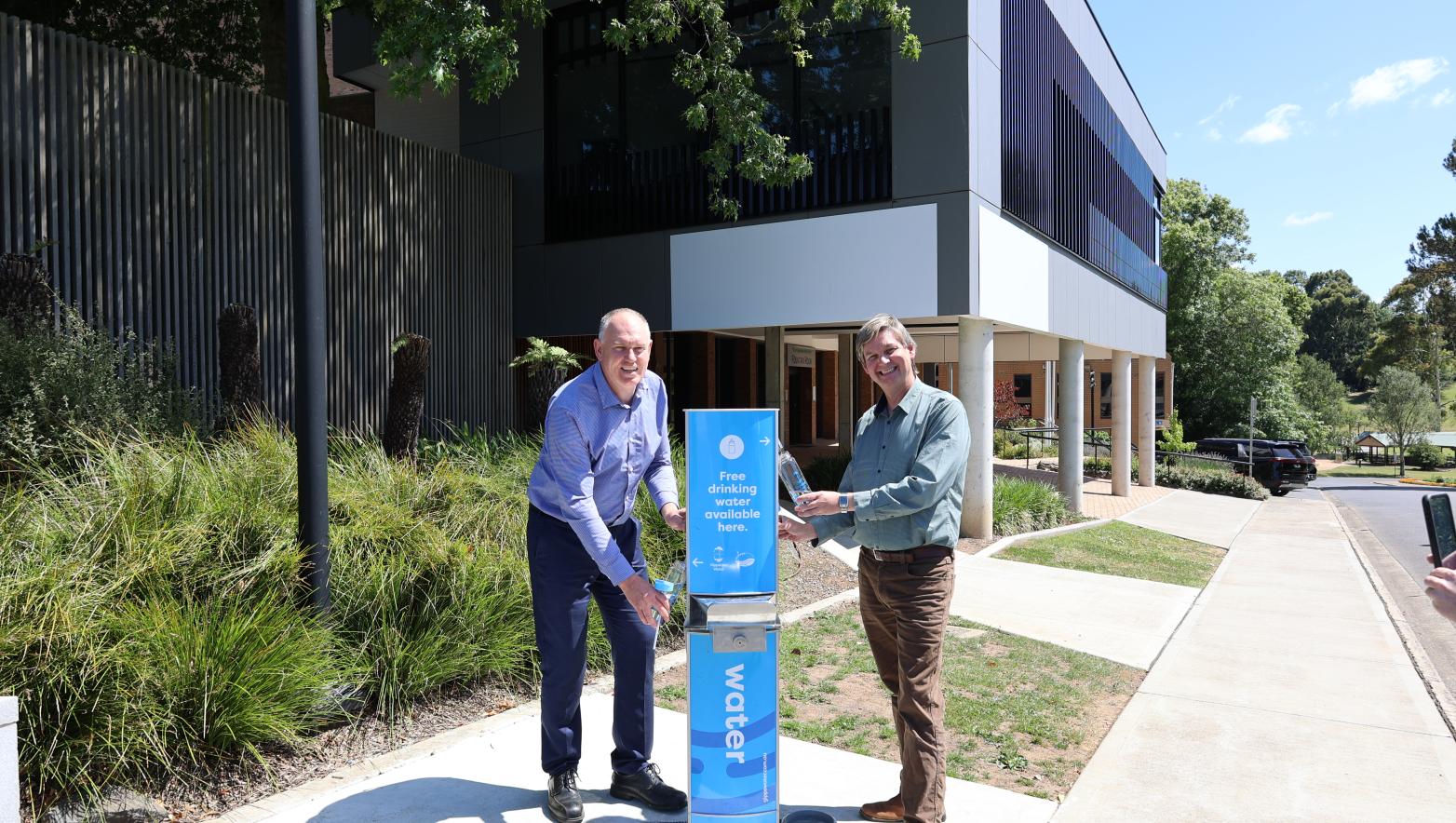 Men stand on either side of blue water fountain.