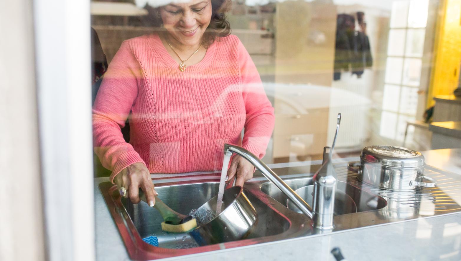 Woman washes dishes at sink. 