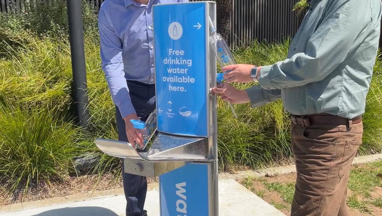 Men stand on either side of blye water fountain.