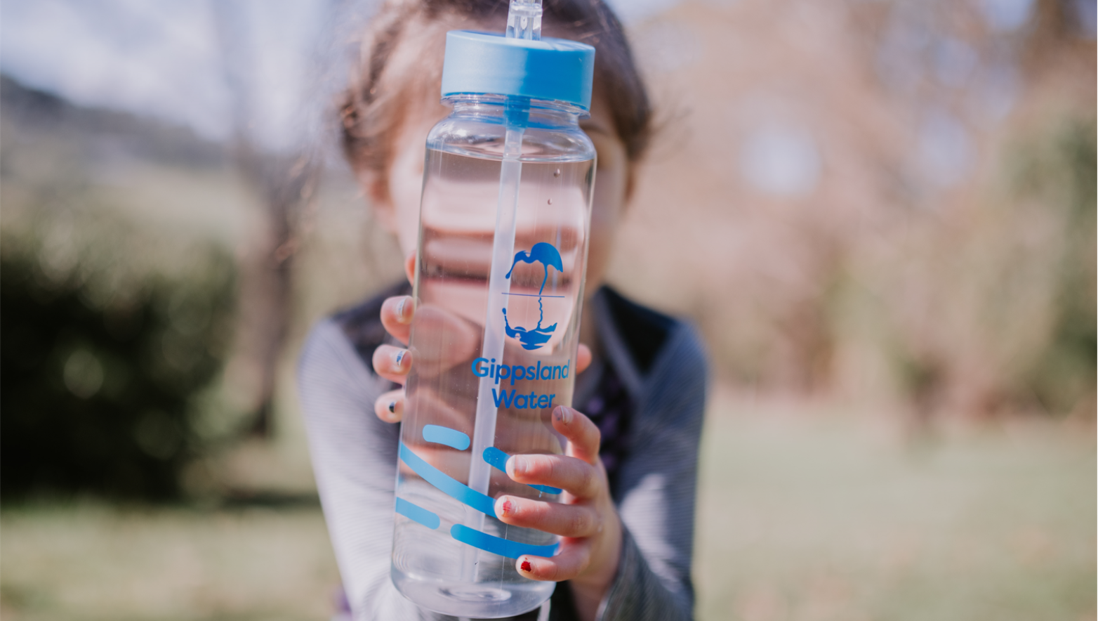 Girl holds Gippsland Water drink bottle up to camera