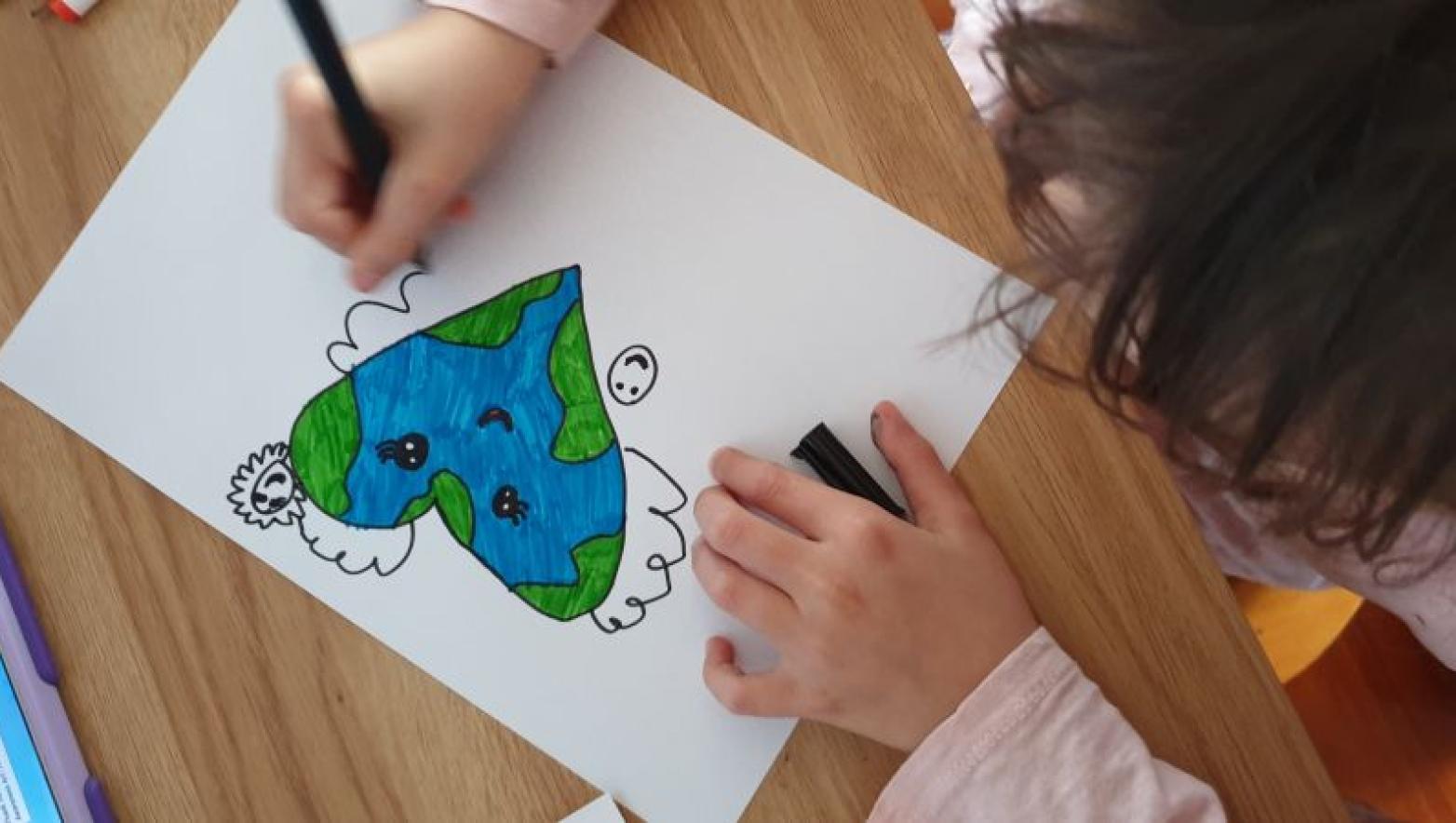 A child's drawing of a heart coloured in like the earth. 