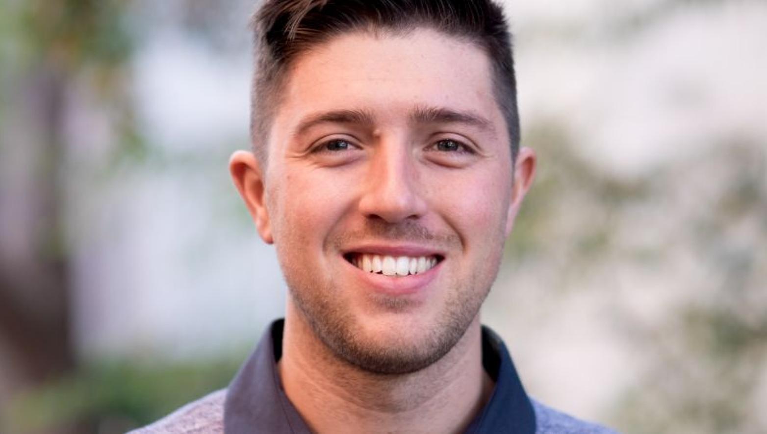 Young man smiles at camera in a close up shot. 