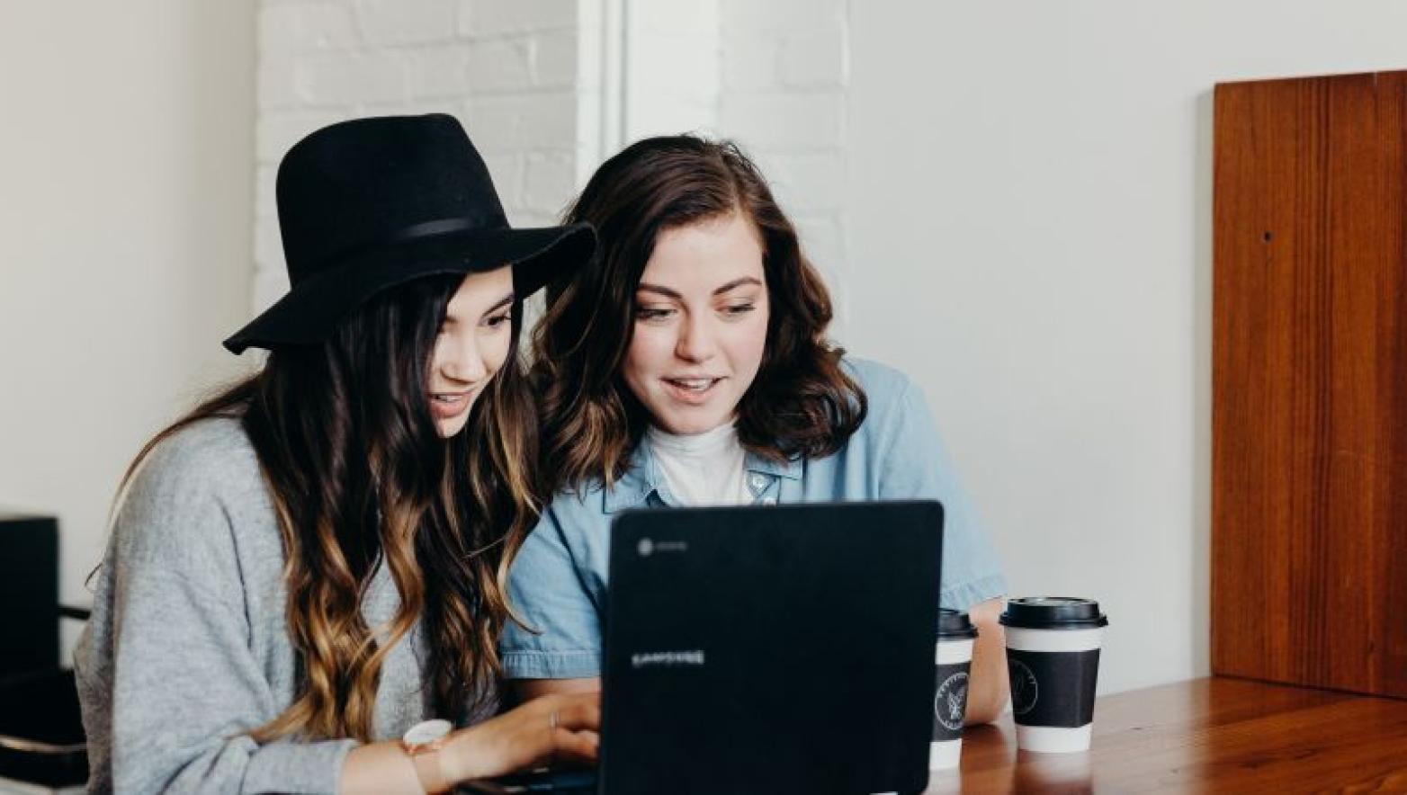 Two girls look at computer. 