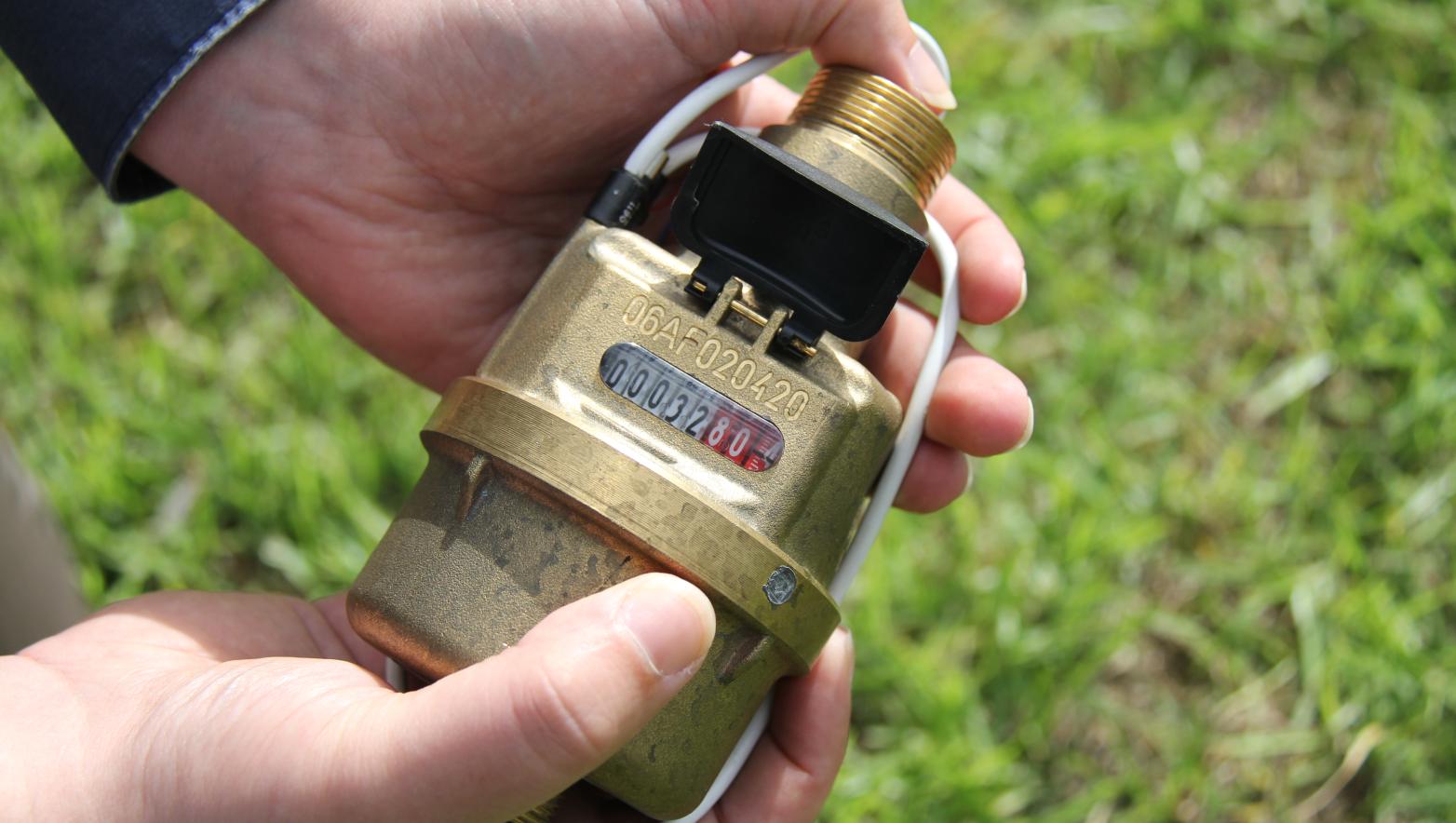 A person holds a water meter in their hands. 