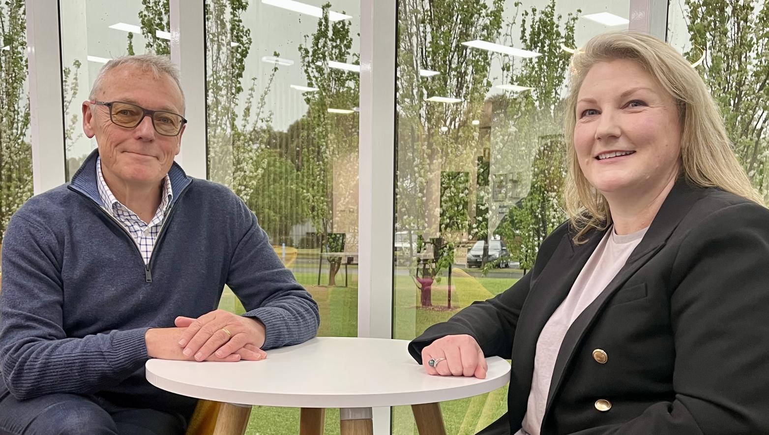 Man and woman sit together at table. They smile at camera