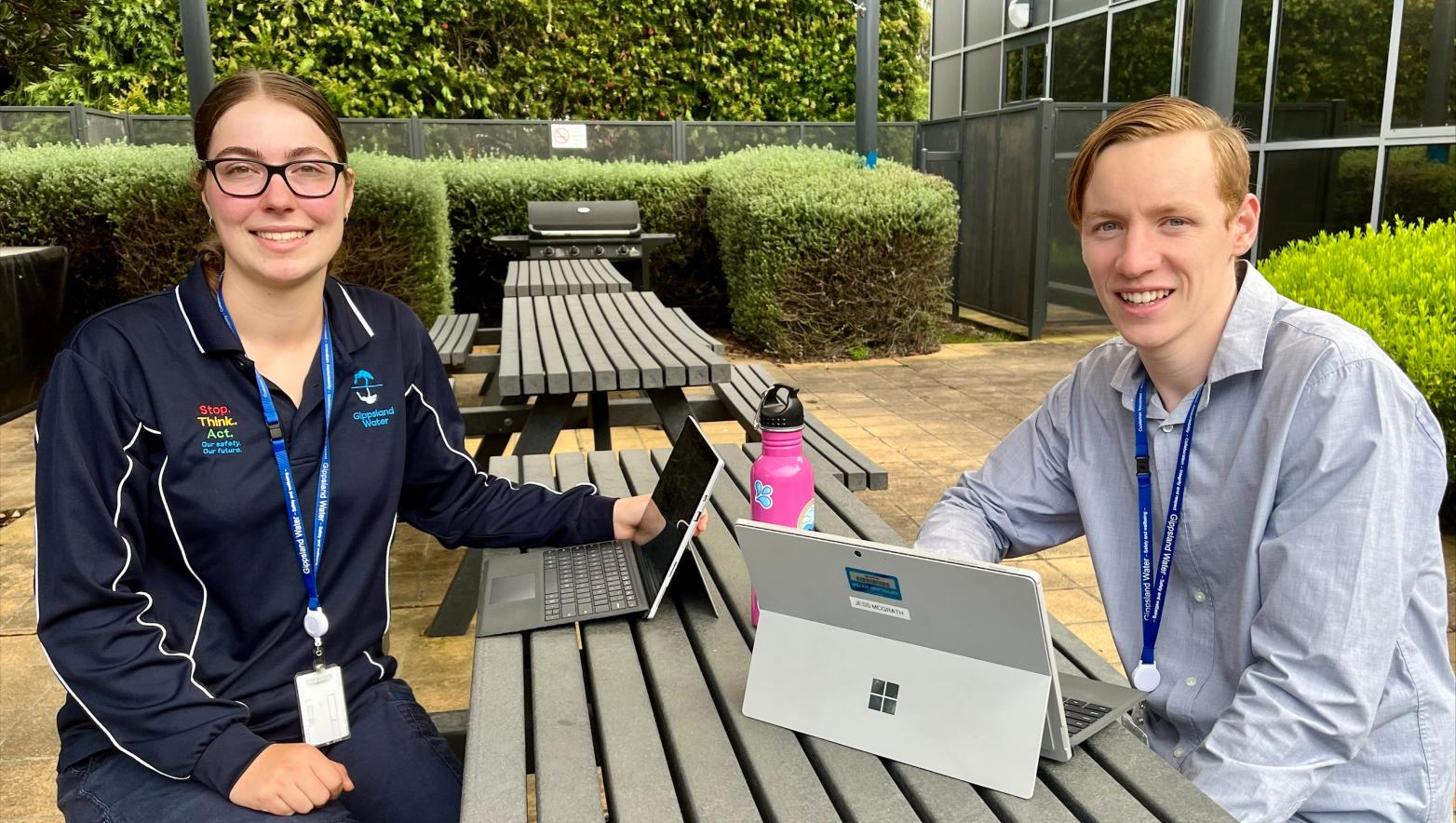 Image of two vacation students sitting at a table and smiling at the camera