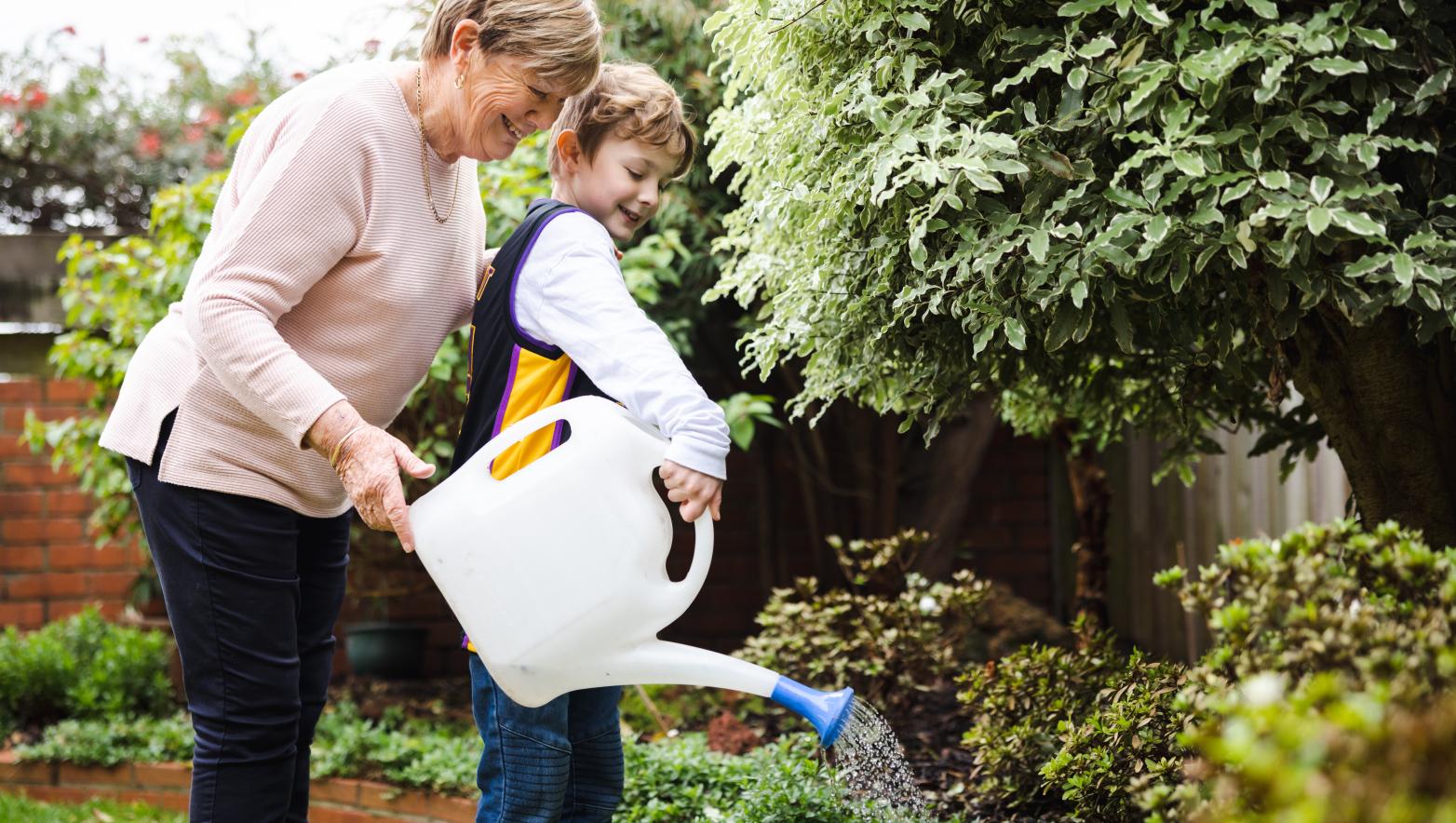 Two people hand watering garden.