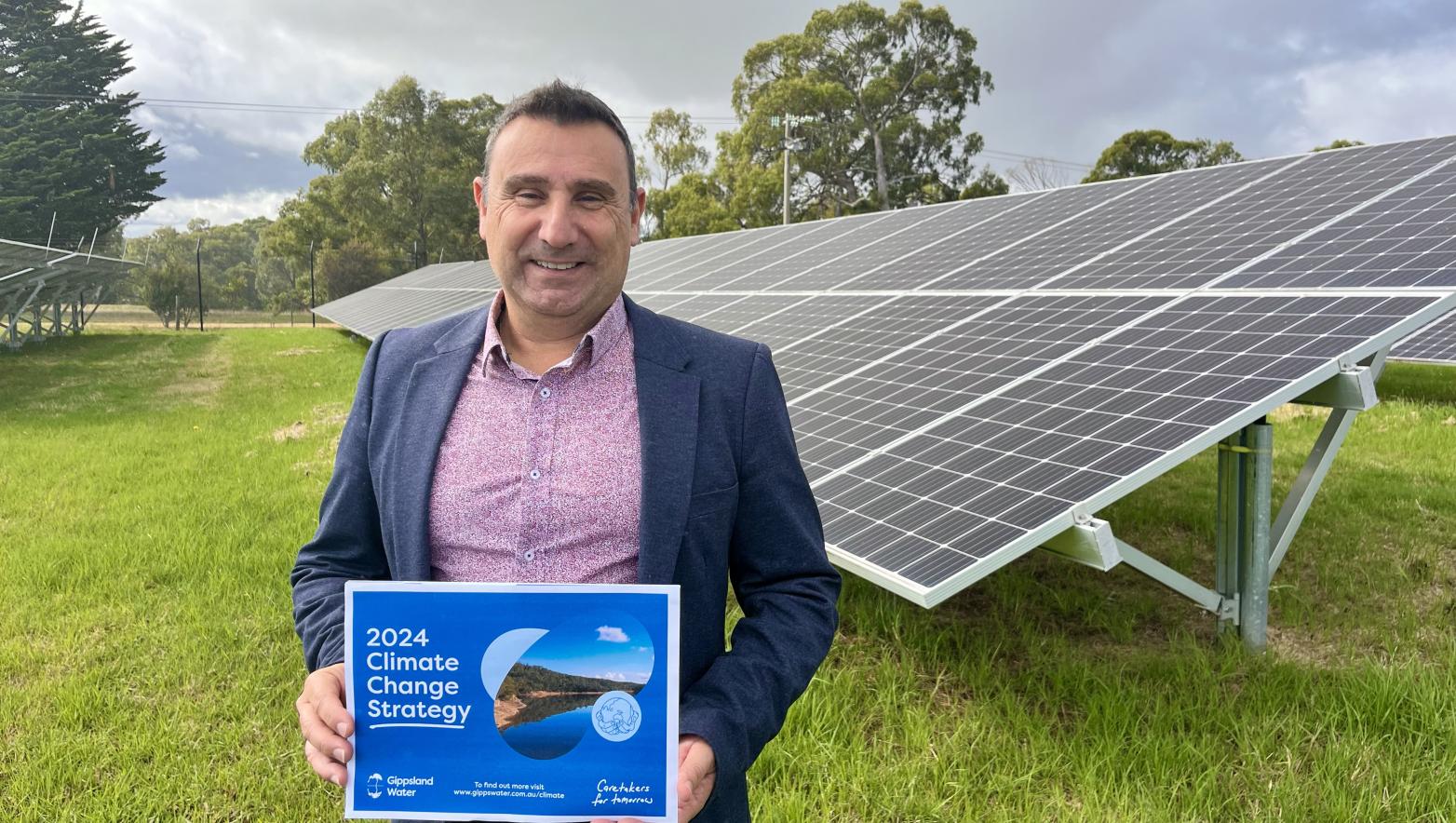 Man holds strategy booklet in front of large solar array