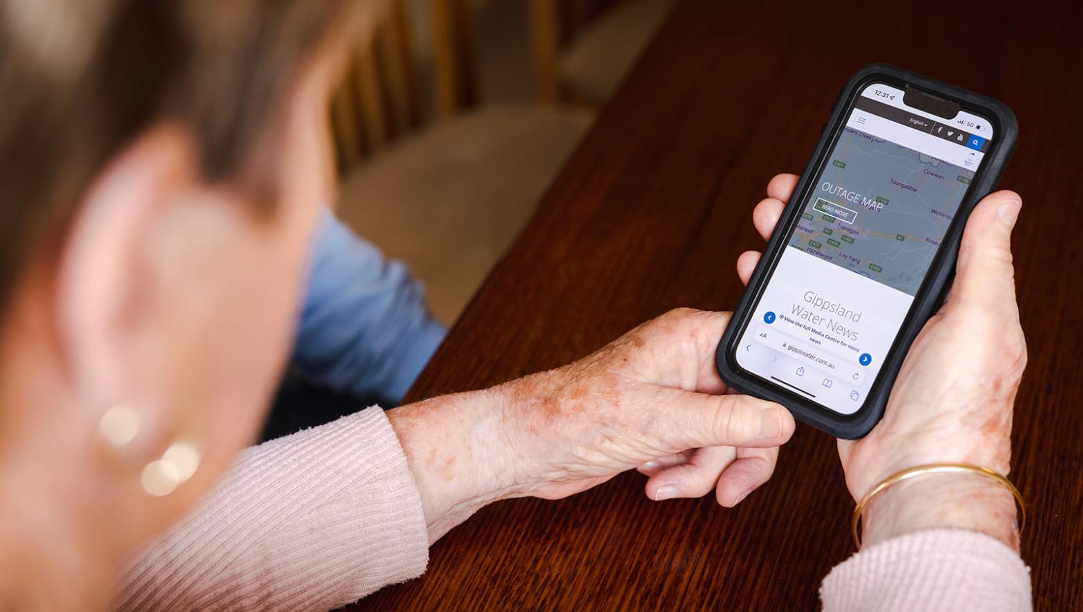 Person holds phone with Gippsland Water website