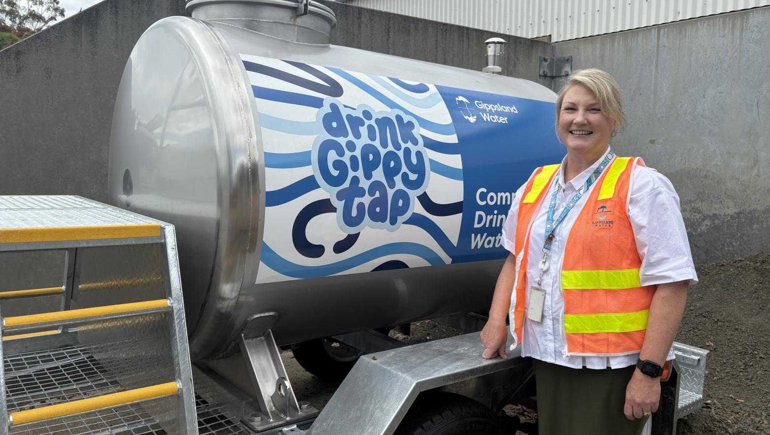 Woman stands in front of water trailer